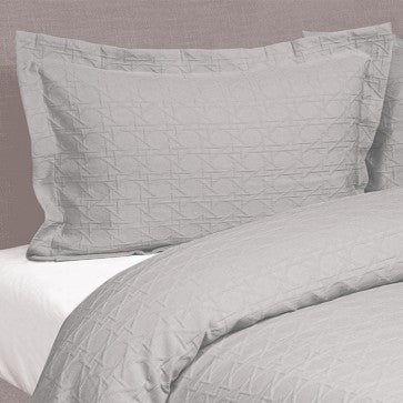 Gray quilted bedding set on a bed with a neutral background