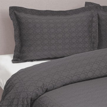 Gray quilted bedding set on a bed with a neutral background